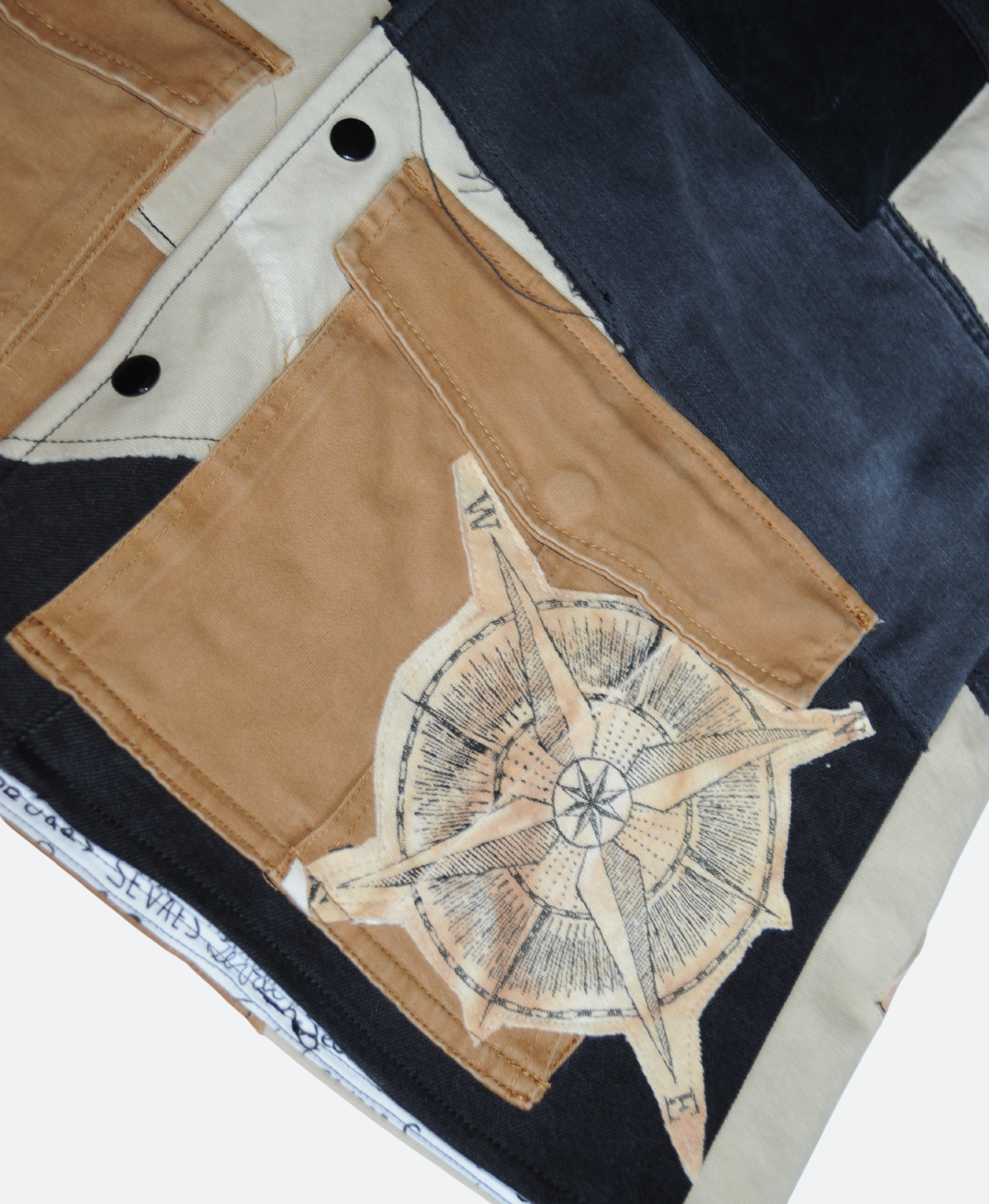 Kompas detail zak Caribbean upcycled denim utility vest in aardetinten: Zwart, Beige en Bruin. Handgemaakt in Rotterdam door Sevaes.